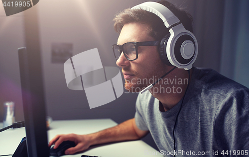 Image of man in headset playing computer video game at home