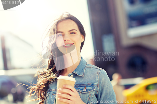 Image of happy young woman drinking coffee on city street