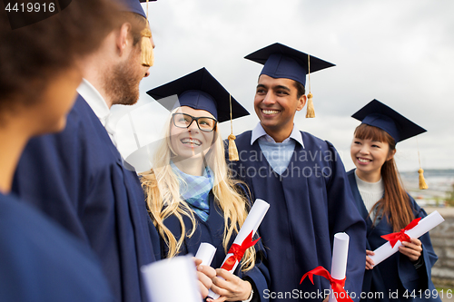 Image of happy students in mortar boards with diplomas