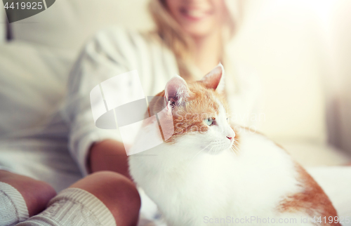 Image of happy young woman with cat in bed at home