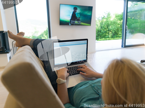 Image of Young woman using laptop at home