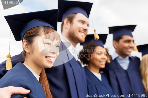 Image of happy students or bachelors in mortar boards