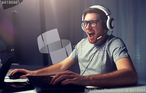 Image of man in headset playing computer video game at home