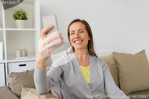 Image of happy woman taking selfie by smartphone at home