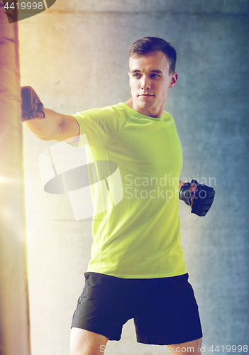 Image of young man in gloves boxing with punching bag