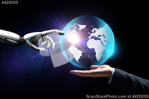 Image of human and robot hand with virtual earth hologram