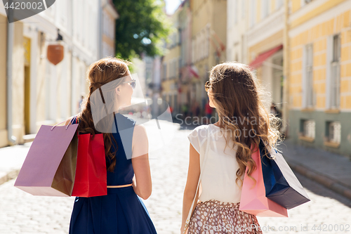 Image of happy women with shopping bags on city street