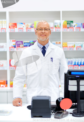 Image of senior apothecary at pharmacy cash register