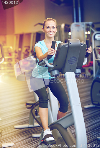 Image of smiling woman exercising on exercise bike in gym