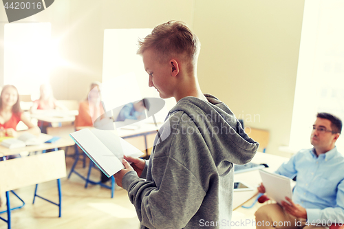 Image of student boy with notebook and teacher at school