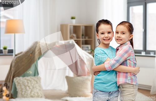 Image of happy smiling little girls hugging at home