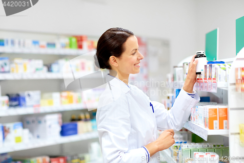 Image of happy female apothecary with drug at pharmacy