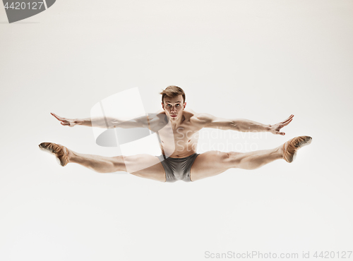 Image of Athletic ballet dancer in a perfect shape performing over the grey background.