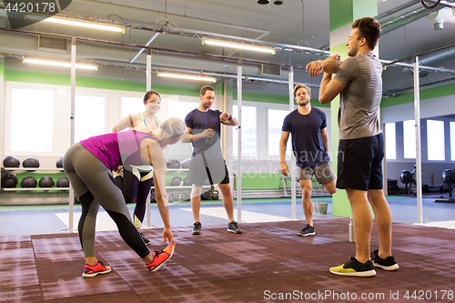 Image of group of happy friends stretching in gym