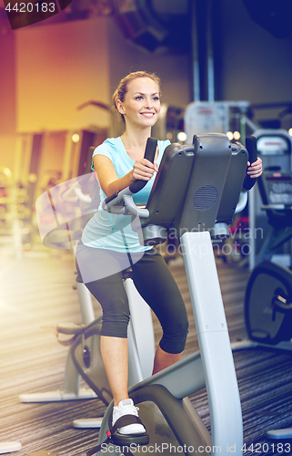 Image of smiling woman exercising on exercise bike in gym