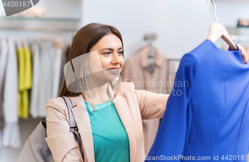 Image of happy young woman choosing clothes in mall