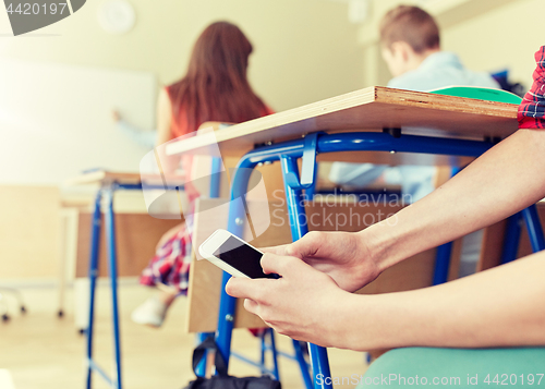 Image of student boy with smartphone texting at school