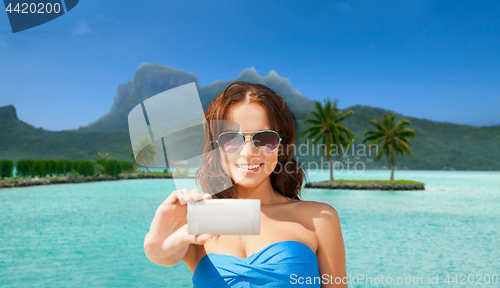 Image of woman taking selfie by smartphone on bora bora