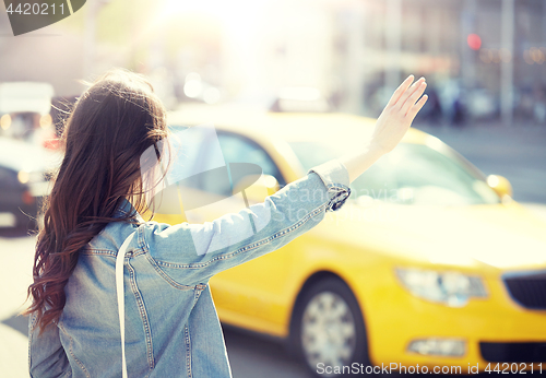 Image of young woman or girl catching taxi on city street