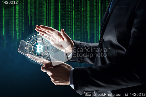 Image of businessman with tablet pc and bitcoin hologram