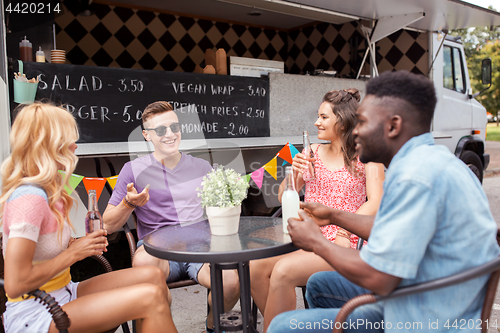 Image of friends with drinks sitting at table at food truck