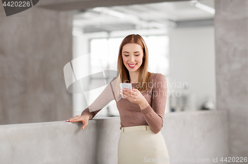Image of happy businesswoman with smartphone at office