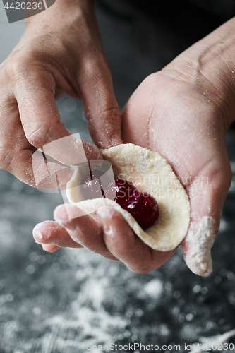 Image of Woman cook manually sculpts dumplings stuffed with cherries