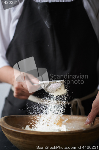 Image of Female hands sifting flour to bowl.