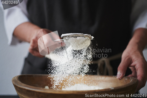 Image of Female hands sifting flour to bowl.