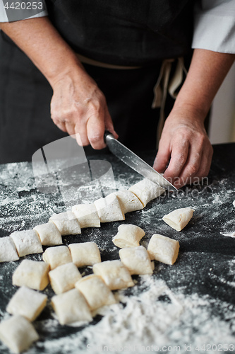 Image of Women\'s hands cut the dough into pieces with kitchen knife