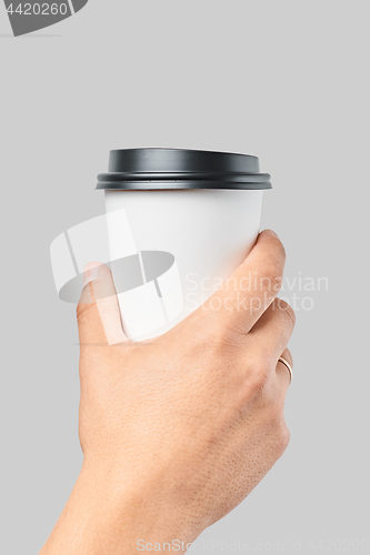 Image of Mockup of men\'s hand holding white paper large size cup with black cover