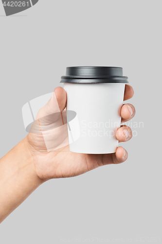 Image of Mockup of men\'s hand holding white paper small size cup with black cover