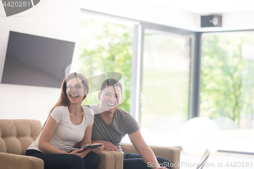 Image of couple relaxing at  home with tablet and laptop computers