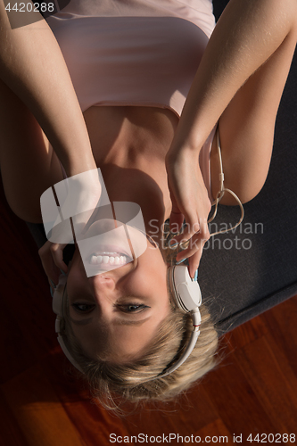 Image of Lovely Blond Woman Listening To Music while resting on couch