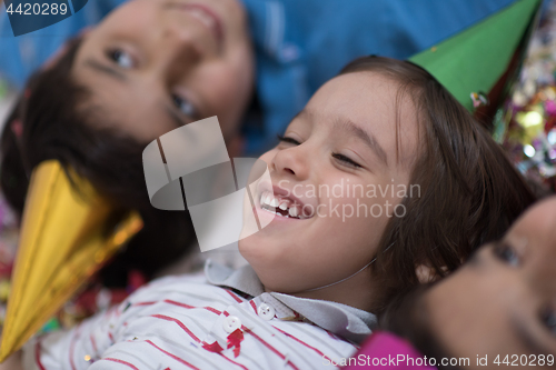 Image of kids  blowing confetti while lying on the floor