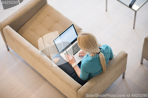 Image of Young woman using laptop at home