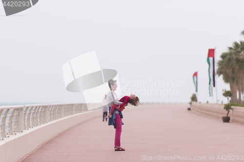 Image of mother and cute little girl on the promenade by the sea