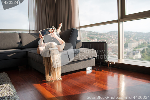 Image of Lovely Blond Woman Listening To Music while resting on couch