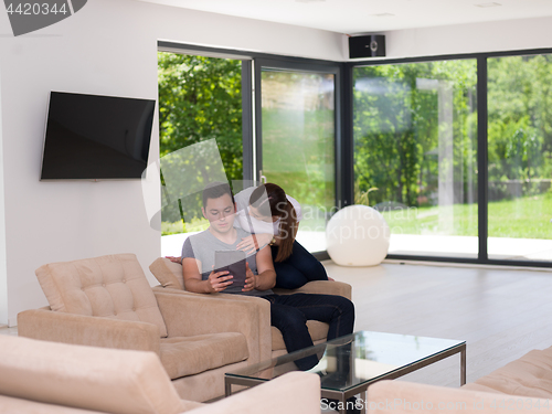 Image of couple relaxing at  home with tablet computers