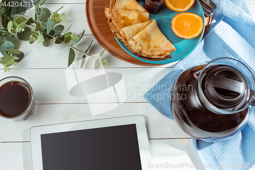 Image of The tablet and pancakes with juice. Healthy breakfast