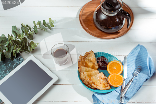 Image of The tablet and pancakes with juice. Healthy breakfast