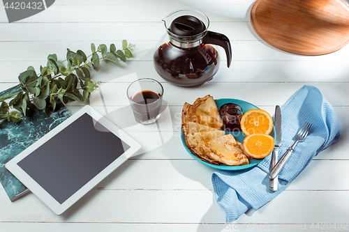 Image of The tablet and pancakes with juice. Healthy breakfast