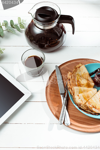 Image of The tablet and pancakes with juice. Healthy breakfast