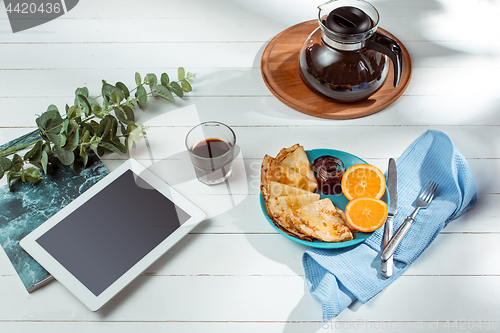 Image of The tablet and pancakes with juice. Healthy breakfast