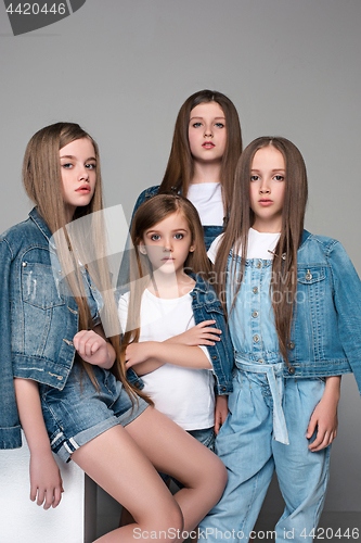 Image of Three happy girls sitting together and looking at camera. Isolated over white.