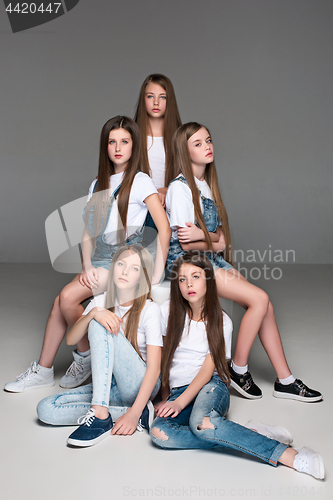 Image of Three happy girls sitting together and looking at camera. Isolated over white.