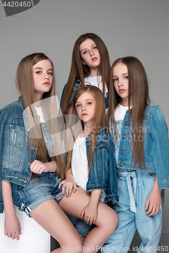 Image of Three happy girls sitting together and looking at camera. Isolated over white.