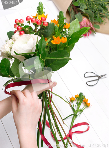Image of Female florist making beautiful bouquet at flower shop
