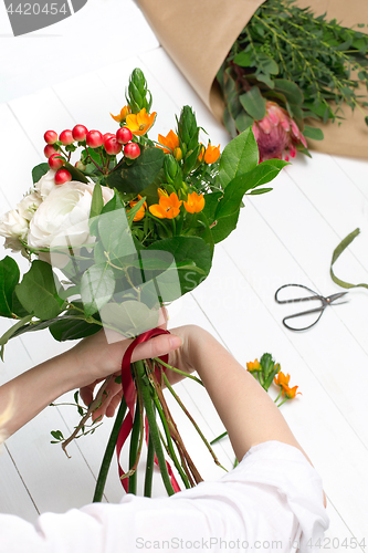 Image of Female florist making beautiful bouquet at flower shop