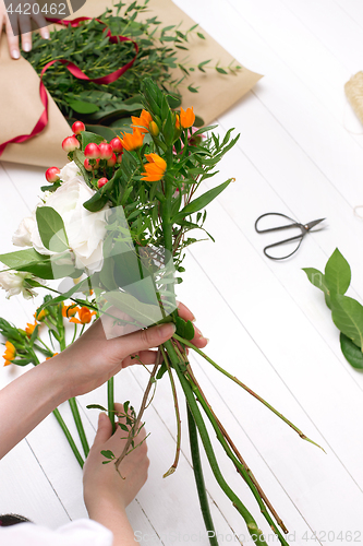 Image of Female florist making beautiful bouquet at flower shop